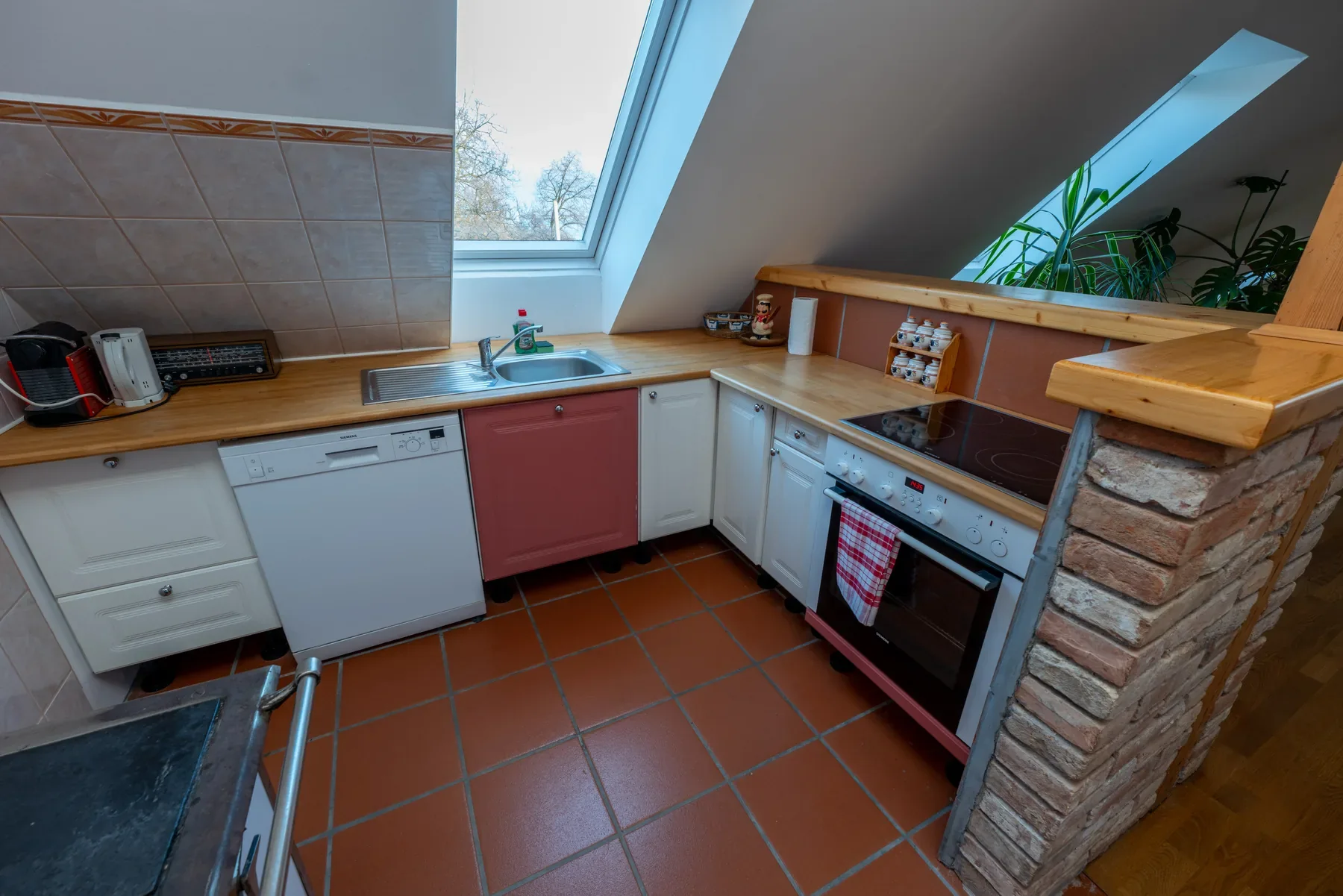 Kitchen in Apartment Modern with white and red cabinetry, skylight and open connection to the living area