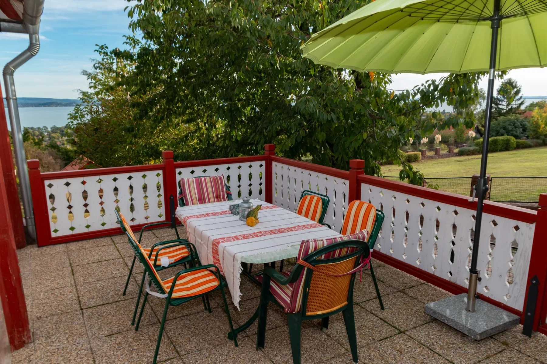 Shared garden terrace at Tabódy Villa with dining table, parasol and Lake Balaton view